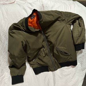 Green jacket with a black neck line and orange in the inside of the jacket.